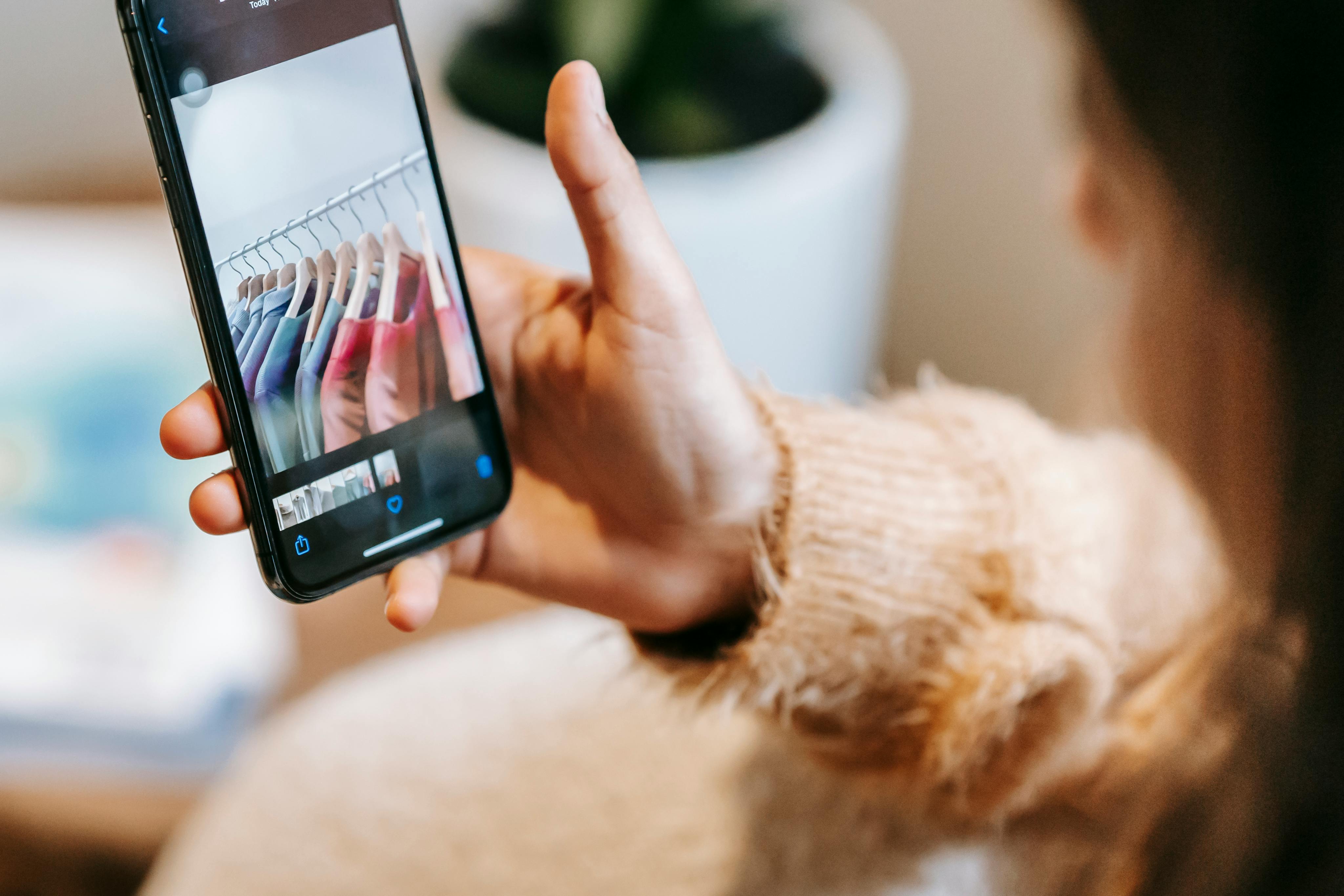 スマホでクローゼットの服を確認している女性