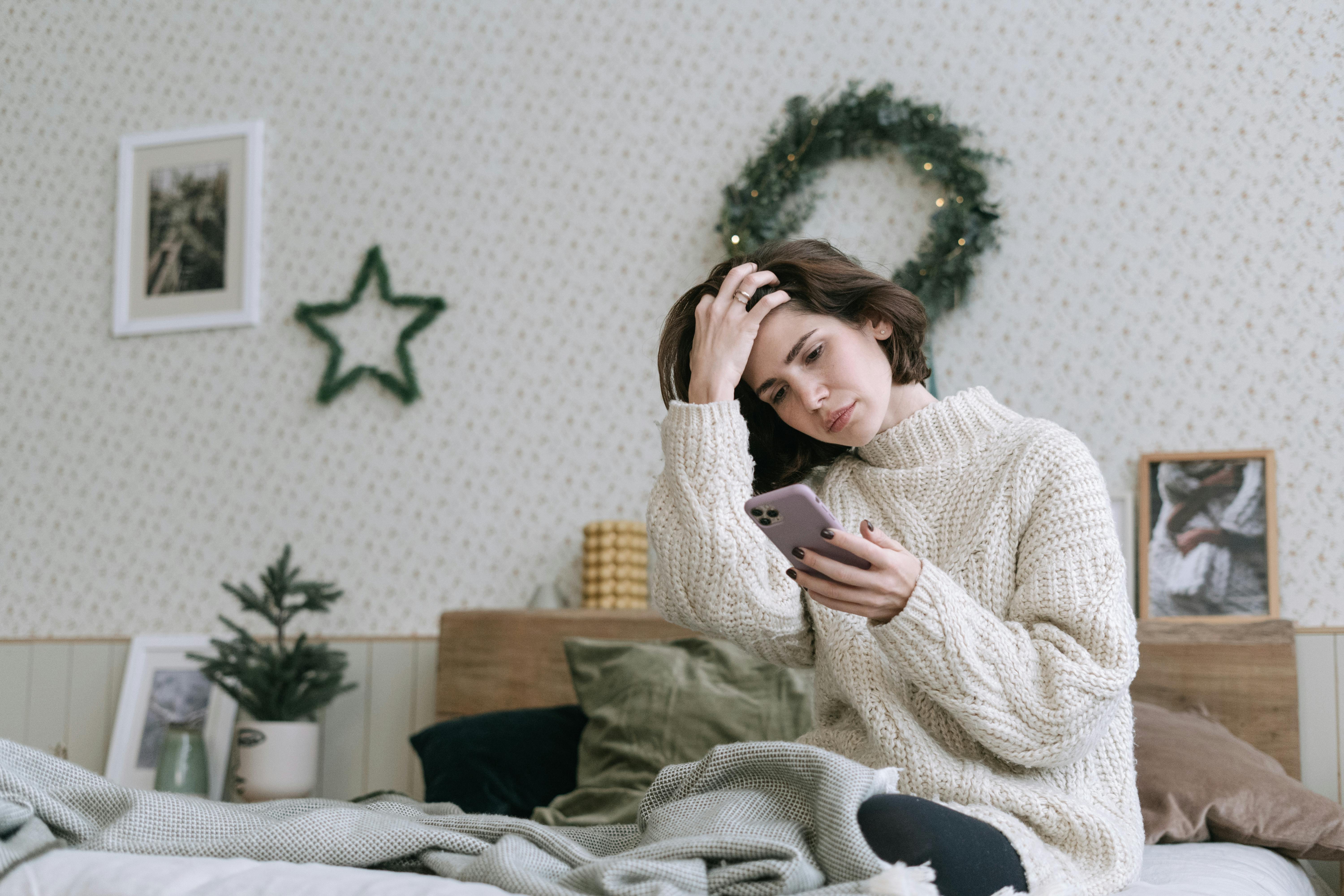 スマホの画面を見て悩んでいる女性